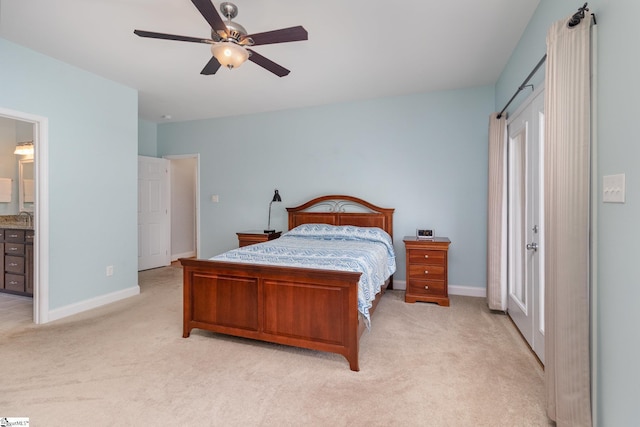 bedroom featuring ceiling fan, ensuite bath, sink, and light carpet