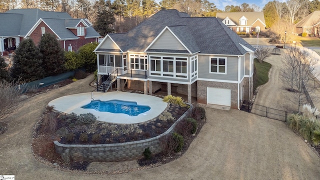 rear view of property with a garage and a sunroom