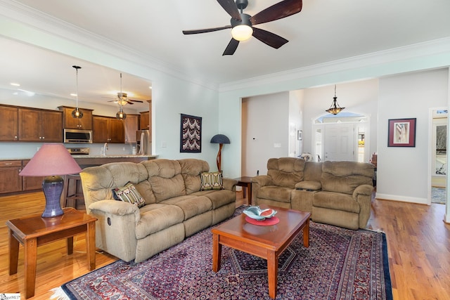 living room featuring ornamental molding, ceiling fan, and light wood-type flooring