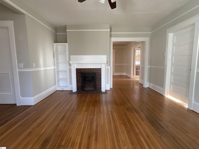 unfurnished living room featuring ceiling fan, dark hardwood / wood-style flooring, and a brick fireplace