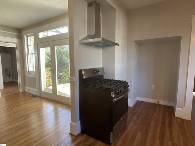 kitchen with wall chimney range hood, dark wood-type flooring, and stainless steel range with gas stovetop