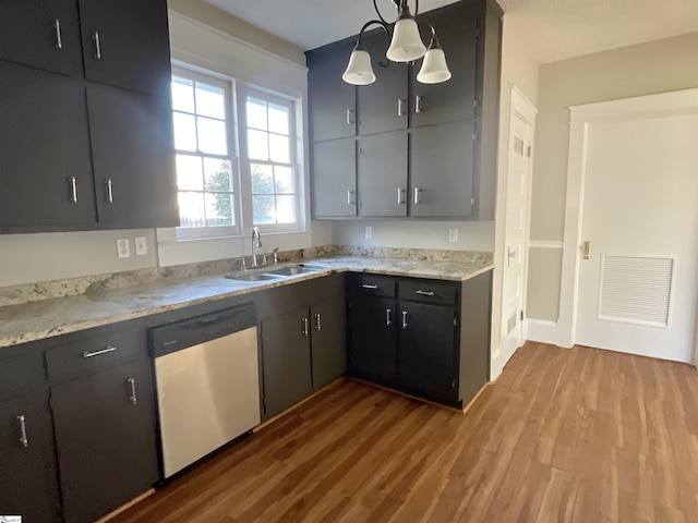 kitchen with hanging light fixtures, sink, stainless steel dishwasher, and light hardwood / wood-style flooring