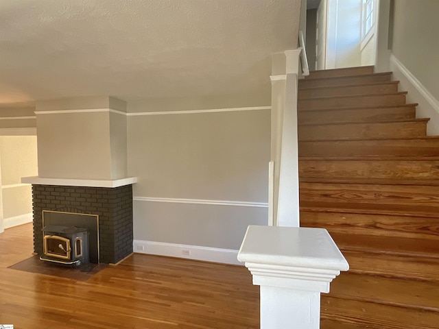 staircase with wood-type flooring, a textured ceiling, and a wood stove