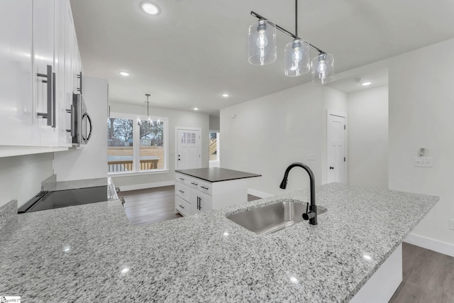 kitchen with white cabinetry, dark stone counters, decorative light fixtures, and sink