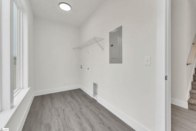 clothes washing area with hookup for a gas dryer, hookup for an electric dryer, electric panel, and light hardwood / wood-style flooring