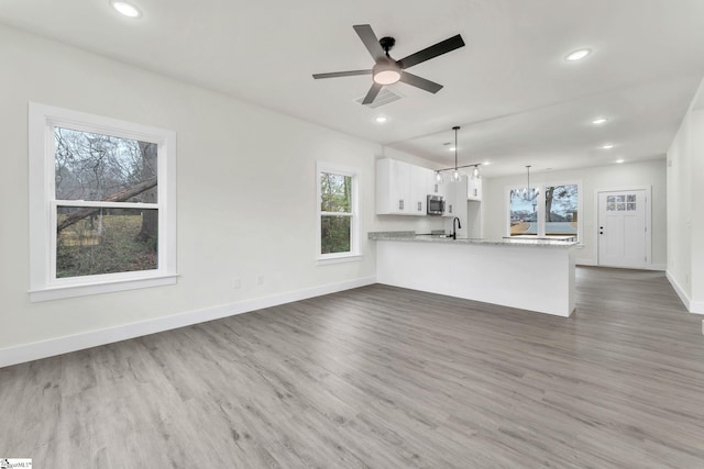 unfurnished living room featuring sink, ceiling fan with notable chandelier, and dark hardwood / wood-style flooring