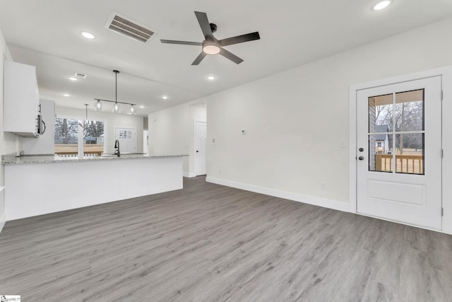 unfurnished living room with sink, hardwood / wood-style floors, and ceiling fan