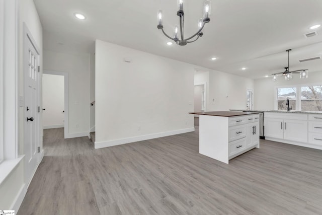 kitchen featuring white cabinetry, decorative light fixtures, a center island, and light hardwood / wood-style floors