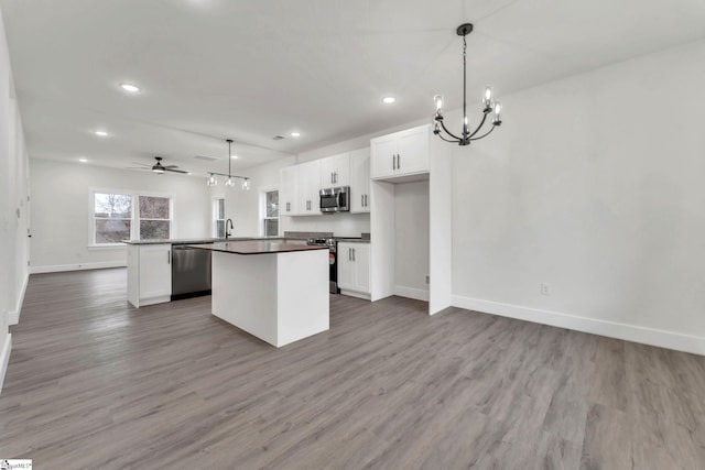 kitchen featuring sink, hanging light fixtures, stainless steel appliances, white cabinets, and a kitchen island