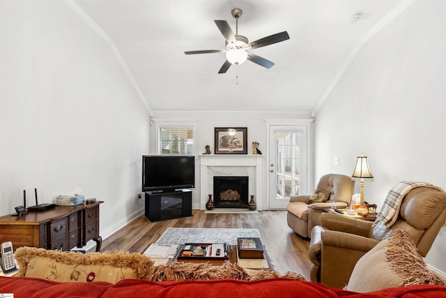 living room with crown molding, ceiling fan, a premium fireplace, and light hardwood / wood-style floors