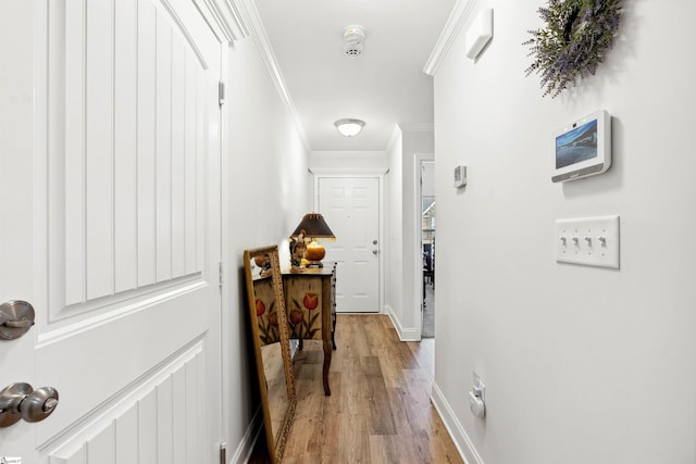 hallway with ornamental molding and light hardwood / wood-style floors