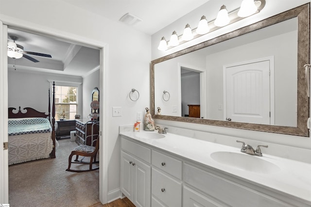 bathroom featuring ceiling fan, ornamental molding, a raised ceiling, and vanity