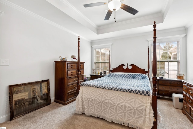 bedroom featuring ornamental molding, light colored carpet, ceiling fan, and a tray ceiling