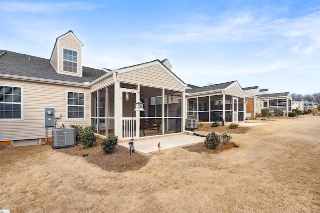 rear view of house featuring central AC unit, a patio area, a sunroom, and a lawn