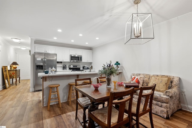 dining space with crown molding, sink, and light wood-type flooring