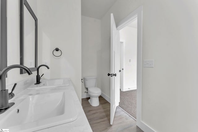 bathroom featuring wood-type flooring, vanity, and toilet