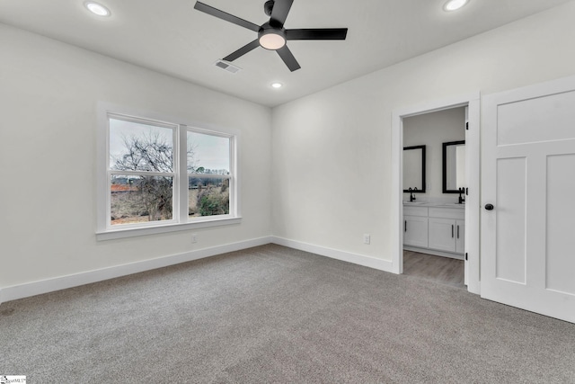 unfurnished bedroom with ensuite bath, light colored carpet, and ceiling fan