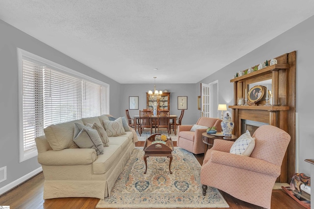 living room with wood-type flooring, an inviting chandelier, and a textured ceiling