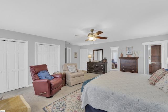 carpeted bedroom featuring ceiling fan and two closets