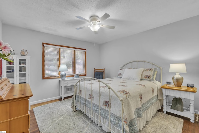 bedroom with hardwood / wood-style flooring, ceiling fan, and a textured ceiling