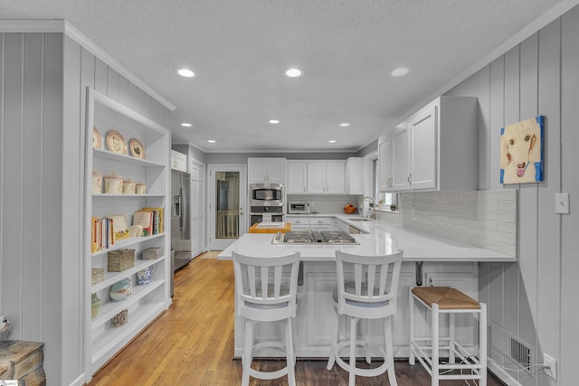 kitchen with a kitchen breakfast bar, stainless steel appliances, kitchen peninsula, and white cabinets