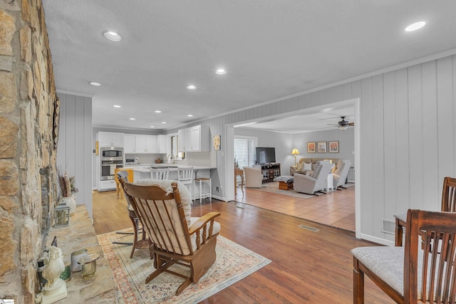 living room with crown molding, ceiling fan, and light hardwood / wood-style flooring