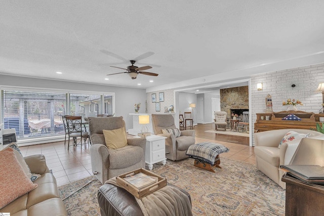 tiled living room with ceiling fan, a fireplace, a textured ceiling, and brick wall