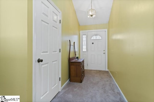 doorway to outside with light carpet, lofted ceiling, and an inviting chandelier