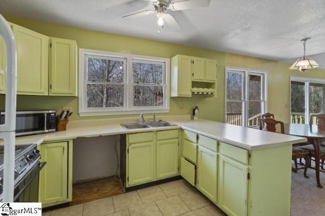 kitchen with pendant lighting, range with gas stovetop, sink, kitchen peninsula, and a textured ceiling