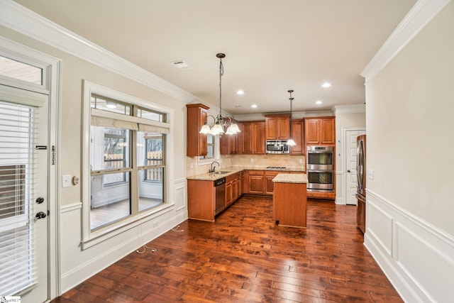 kitchen featuring light stone counters, decorative light fixtures, ornamental molding, appliances with stainless steel finishes, and a kitchen island