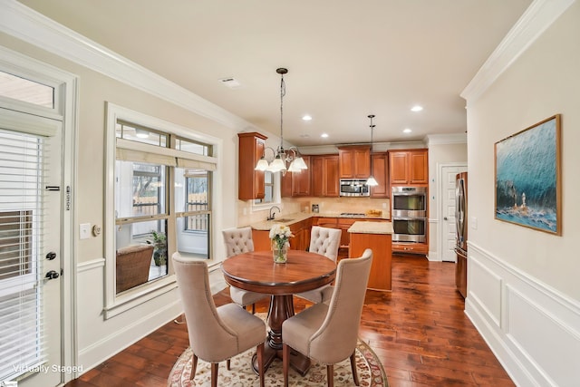 dining space featuring crown molding, sink, a chandelier, and dark hardwood / wood-style flooring