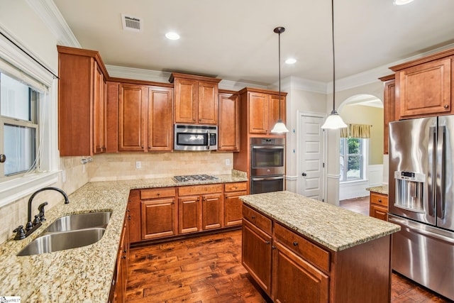 kitchen with pendant lighting, tasteful backsplash, sink, a center island, and stainless steel appliances