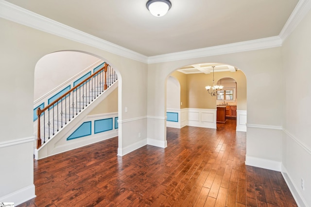 empty room featuring ornamental molding, an inviting chandelier, and dark hardwood / wood-style flooring