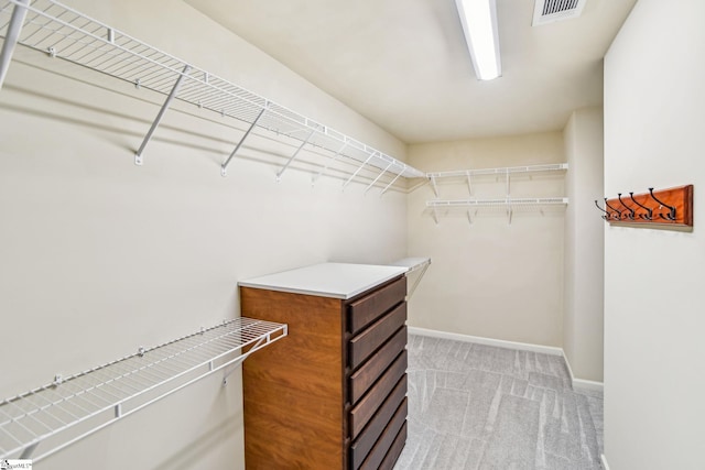 walk in closet featuring light colored carpet