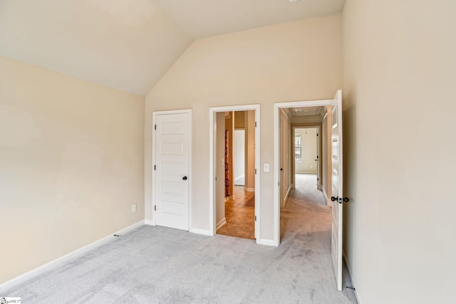 unfurnished bedroom featuring high vaulted ceiling and light colored carpet