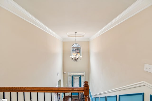 stairs with ornamental molding and a chandelier