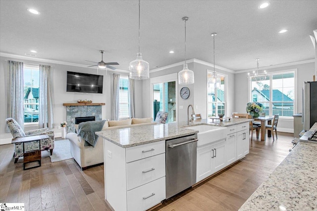 kitchen with dishwasher, white cabinetry, hanging light fixtures, light stone countertops, and an island with sink