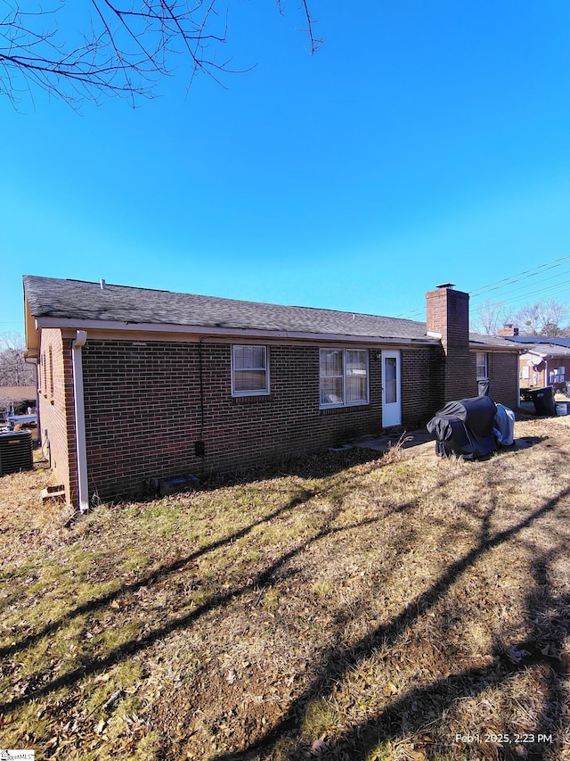 back of property with central AC unit and a lawn