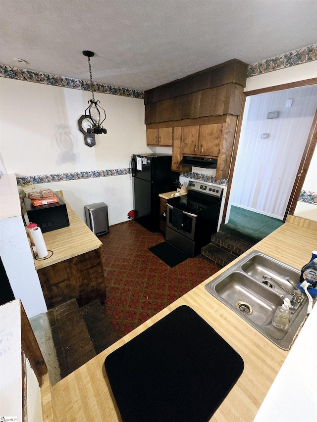 kitchen featuring sink, black fridge, decorative light fixtures, a textured ceiling, and electric range