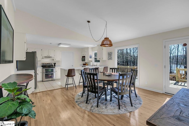 dining room with lofted ceiling and light hardwood / wood-style flooring