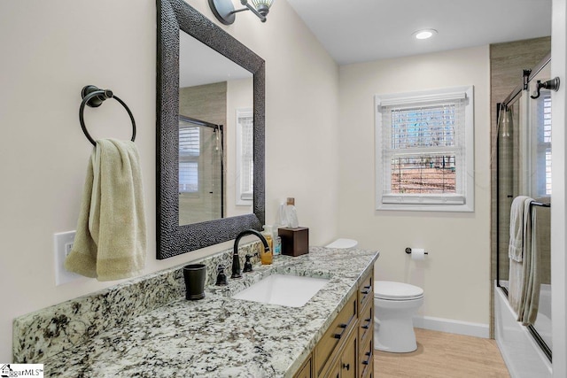 full bathroom featuring hardwood / wood-style flooring, enclosed tub / shower combo, vanity, and toilet