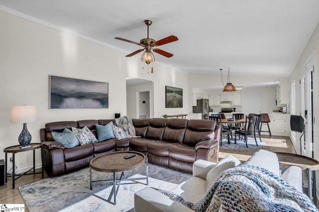 living room with light hardwood / wood-style flooring, vaulted ceiling, ornamental molding, and ceiling fan