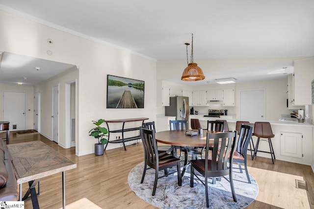 dining space with ornamental molding and light hardwood / wood-style floors