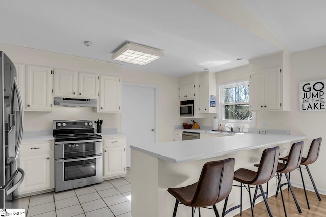 kitchen with white cabinetry, sink, kitchen peninsula, and appliances with stainless steel finishes