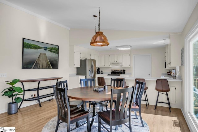 dining area featuring crown molding, sink, and light wood-type flooring