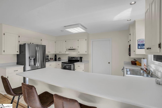 kitchen featuring sink, appliances with stainless steel finishes, kitchen peninsula, light hardwood / wood-style floors, and white cabinets