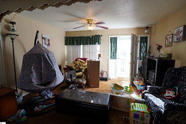 interior space featuring ceiling fan, carpet, and a textured ceiling