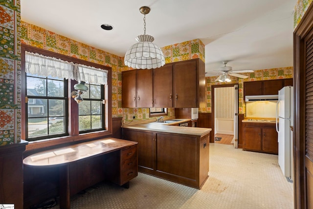 kitchen featuring dark brown cabinetry, sink, decorative light fixtures, kitchen peninsula, and white fridge