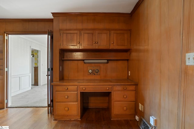 office space featuring ornamental molding, built in desk, and light wood-type flooring