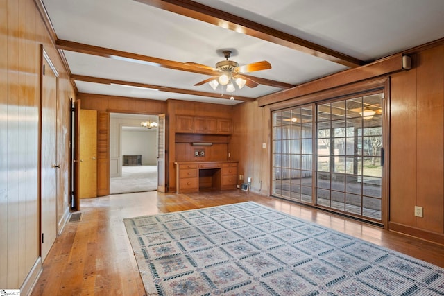 unfurnished living room with light hardwood / wood-style floors, beamed ceiling, and wood walls